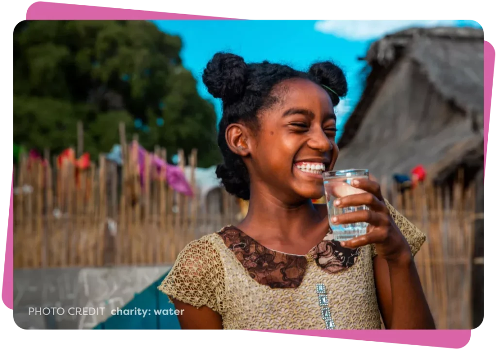 Young girl smiling while holding a glass of water