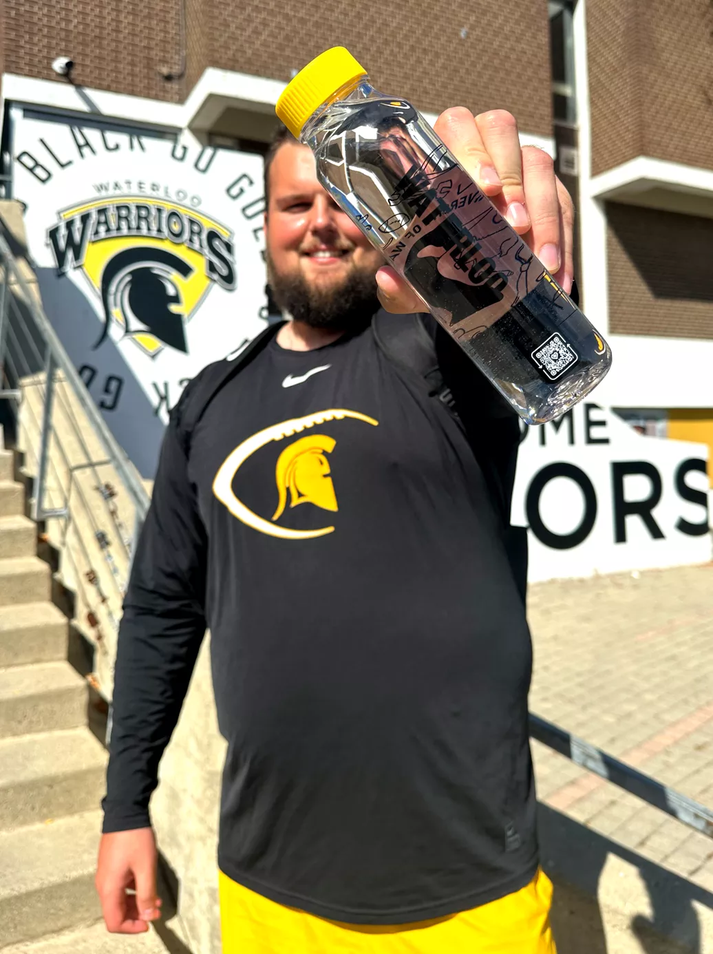 University of Waterloo football player holding a cupanion bottle to camera