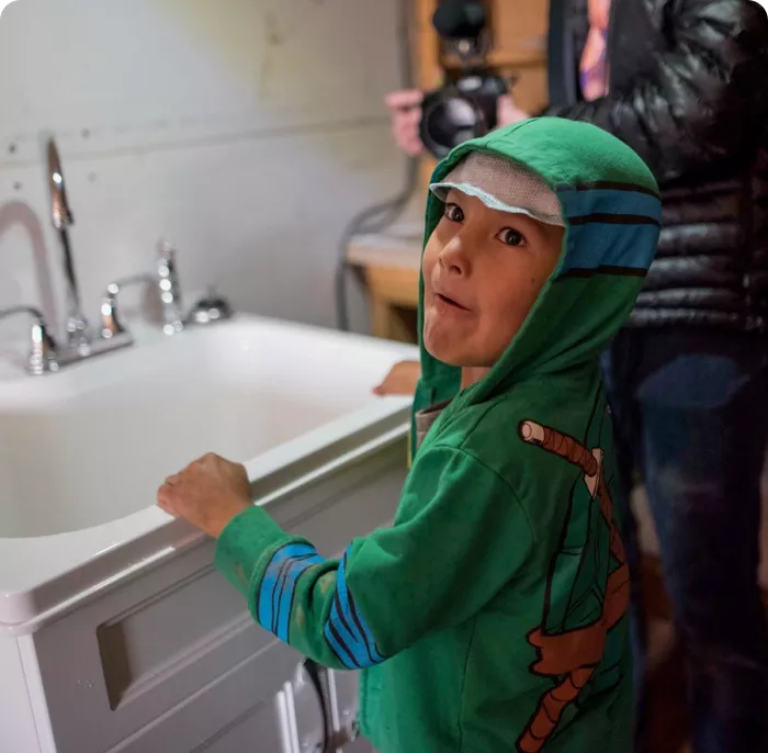 Young boy happy about running water from a tap